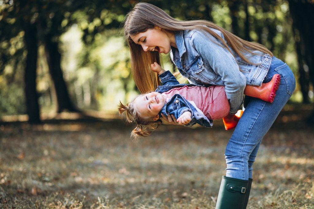 Young mother with her little daughter in an autumn park
